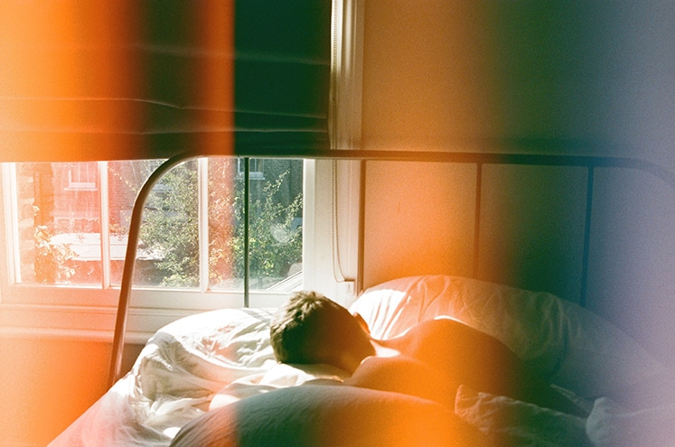 person lying in bed beside window 1572728